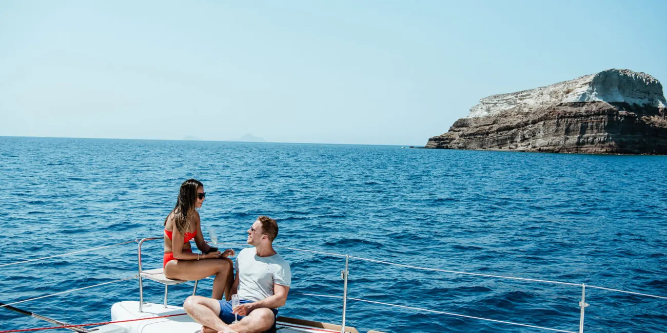 On the bow of our catamaran off Santorini's volcanic coast