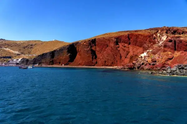 The red volcanic cliffs of Red Beach, Santorini, seen from the water