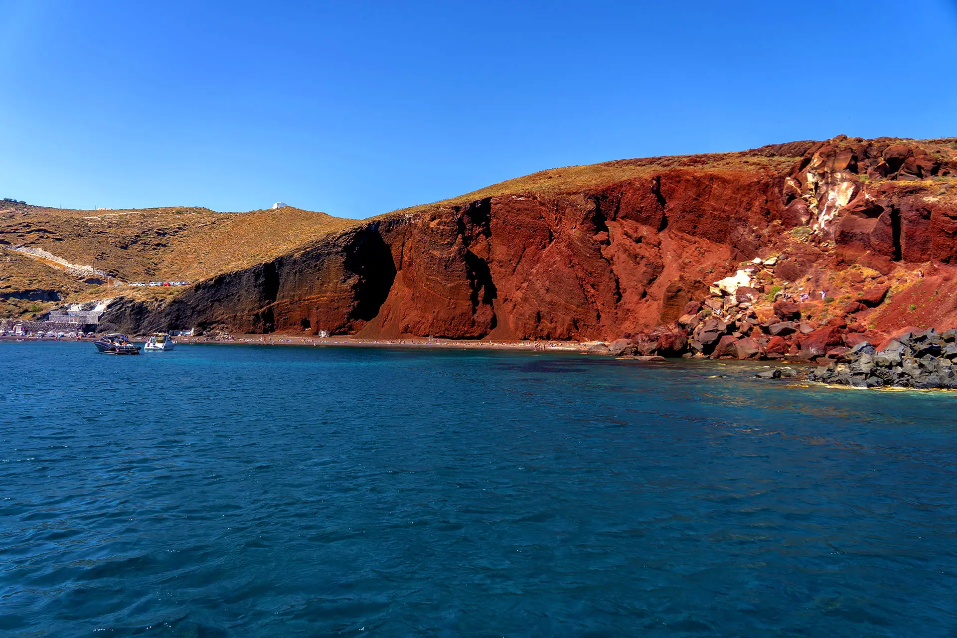 The red volcanic cliffs of Red Beach, Santorini, seen from the water