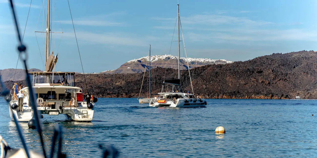 Catamarans in the Santorini caldera with Fira on the clifftop above