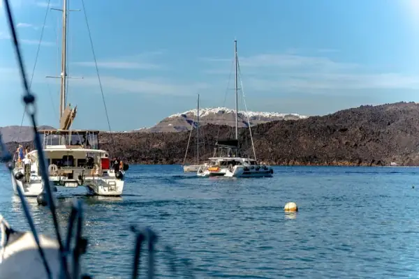 Catamarans in the Santorini caldera with Fira on the clifftop above