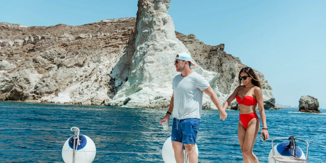 Guests on deck at a swim stop by Santorini's white volcanic cliffs