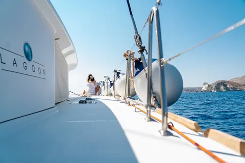 The side deck of the Lagoon catamaran with guests at the bow and the south-coast cliffs ahead